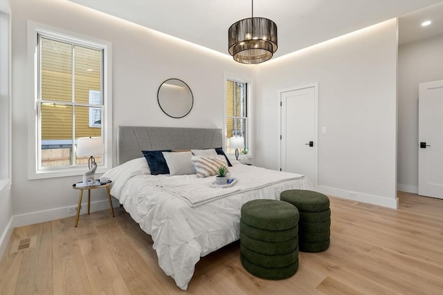 bedroom with a chandelier, light hardwood / wood-style flooring, and multiple windows