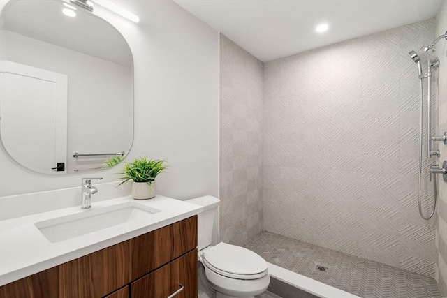 bathroom featuring vanity, toilet, and a tile shower