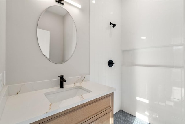 bathroom featuring tiled shower and vanity