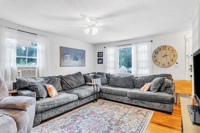 living room with light wood-style floors, ceiling fan, and a textured ceiling