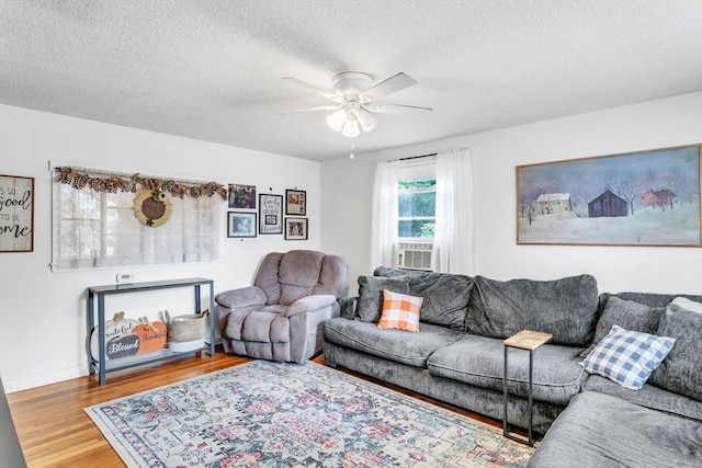 living room with baseboards, a textured ceiling, a ceiling fan, and wood finished floors