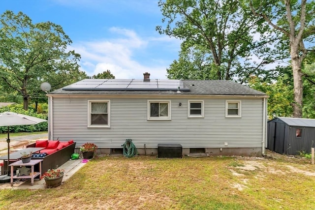 back of house featuring an outbuilding, solar panels, a storage unit, and a lawn