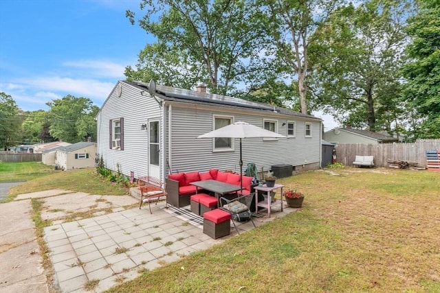 rear view of house featuring a yard, roof mounted solar panels, fence, and a patio