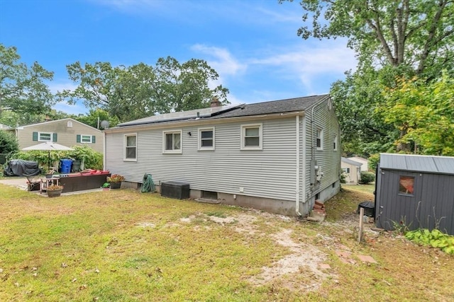 back of property featuring solar panels, a lawn, a chimney, a storage unit, and an outdoor structure