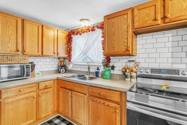 kitchen with stainless steel appliances, light countertops, decorative backsplash, a sink, and a textured ceiling