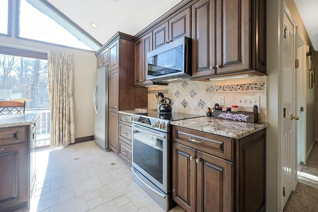 kitchen with light stone countertops, stainless steel appliances, tasteful backsplash, lofted ceiling, and dark brown cabinets