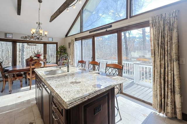 kitchen with sink, a kitchen breakfast bar, beamed ceiling, pendant lighting, and a chandelier