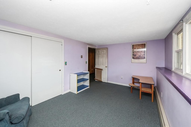 living area with dark carpet and a baseboard heating unit