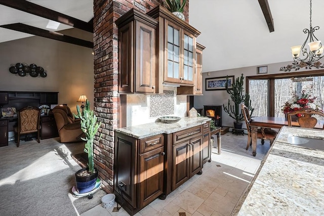 kitchen featuring pendant lighting, lofted ceiling with beams, light stone countertops, tasteful backsplash, and a chandelier