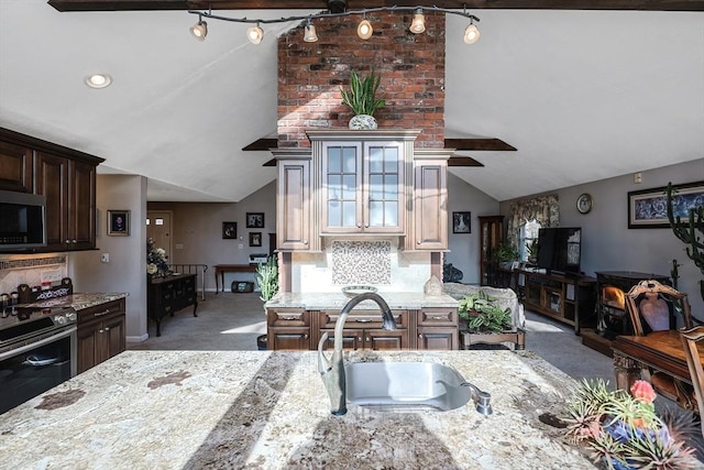 kitchen featuring sink, tasteful backsplash, light stone counters, vaulted ceiling, and stainless steel stove