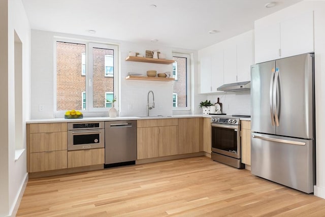 kitchen with sink, light hardwood / wood-style flooring, stainless steel appliances, and white cabinets