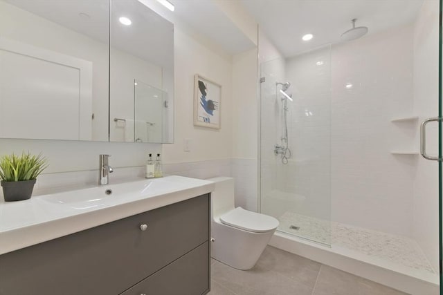 bathroom with tile walls, vanity, walk in shower, toilet, and tile patterned floors