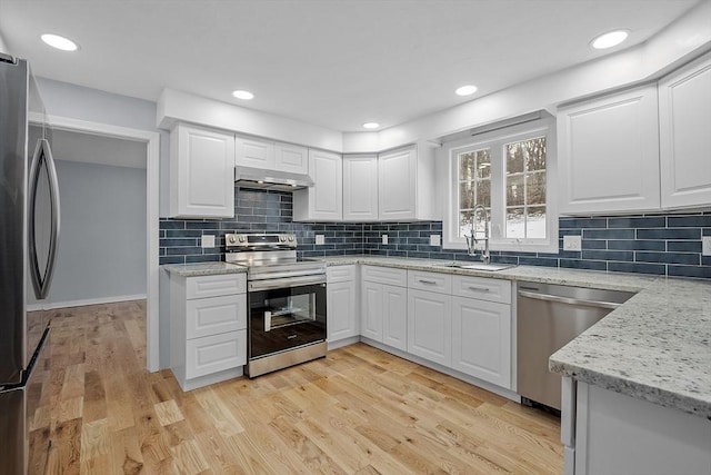 kitchen with appliances with stainless steel finishes, sink, exhaust hood, light hardwood / wood-style floors, and white cabinetry