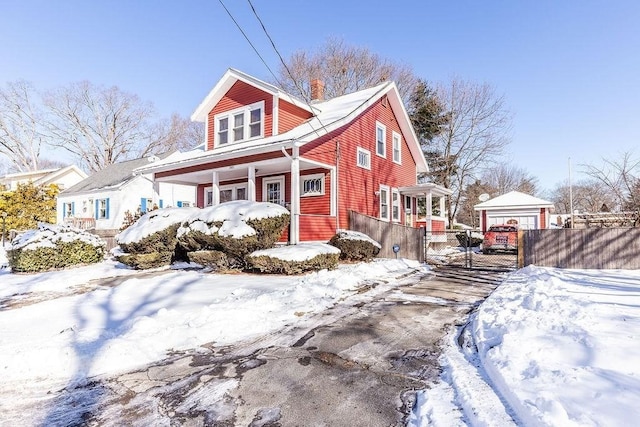 view of snow covered exterior featuring a garage, an outdoor structure, and covered porch