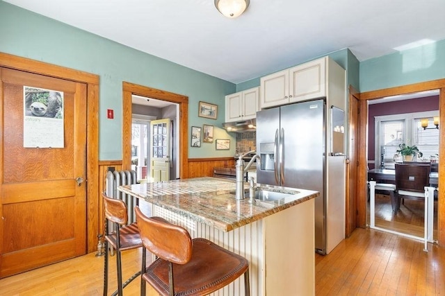 kitchen with a breakfast bar area, light stone countertops, kitchen peninsula, and white cabinets