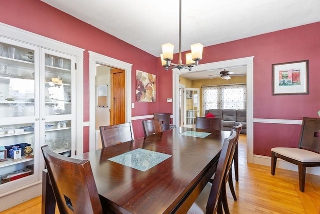 dining space featuring ceiling fan with notable chandelier and light hardwood / wood-style flooring