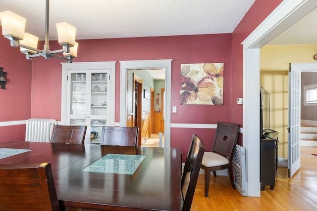 dining space with radiator, a notable chandelier, and light hardwood / wood-style flooring