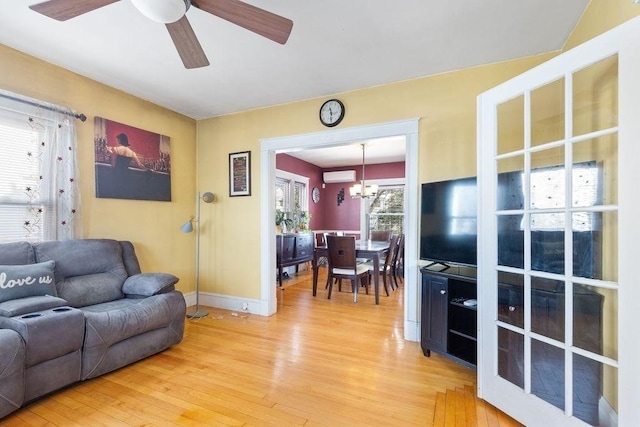 living room featuring ceiling fan with notable chandelier and hardwood / wood-style floors