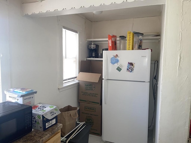 kitchen featuring black microwave and freestanding refrigerator