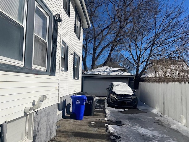 snow covered property with a garage, fence, and an outdoor structure