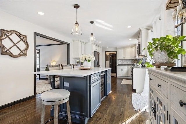 kitchen featuring pendant lighting, a breakfast bar area, white cabinets, decorative backsplash, and a center island