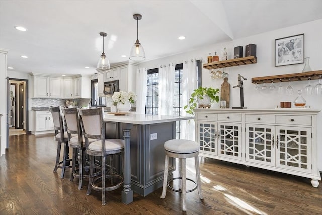 bar featuring white cabinetry, decorative light fixtures, dark hardwood / wood-style flooring, and decorative backsplash