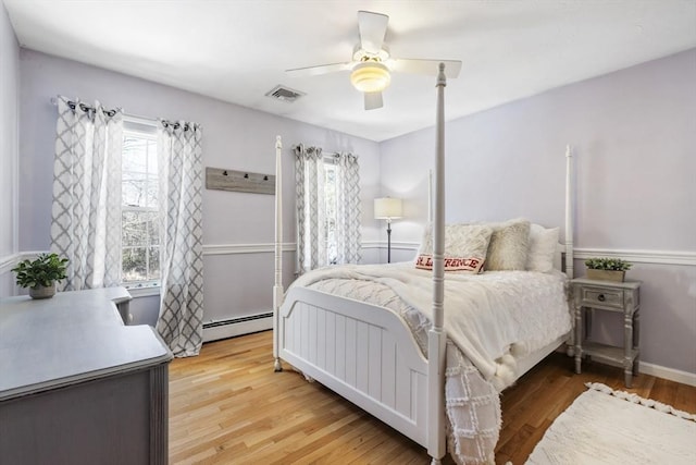 bedroom featuring ceiling fan, wood-type flooring, and a baseboard heating unit