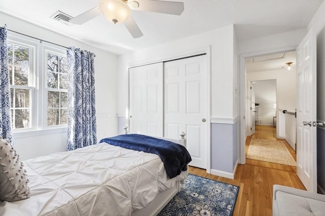 bedroom with ceiling fan, a closet, light hardwood / wood-style floors, and multiple windows