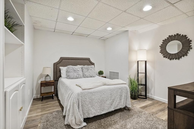 bedroom featuring wood-type flooring and a drop ceiling