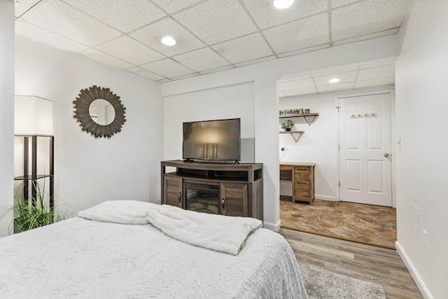 bedroom with wood-type flooring and a paneled ceiling