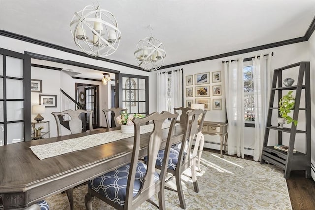 dining area with a notable chandelier, wood-type flooring, and ornamental molding