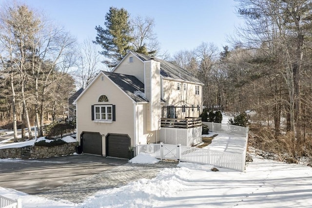 snow covered property with a garage