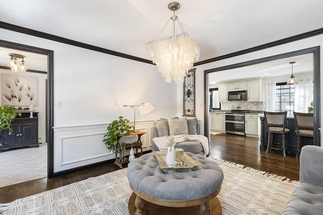 living room with crown molding, dark hardwood / wood-style flooring, and an inviting chandelier