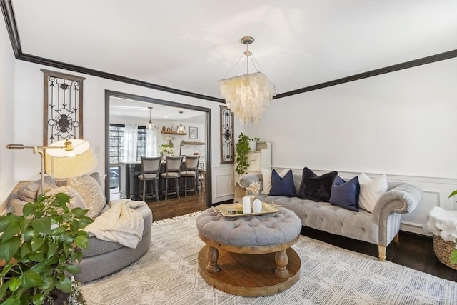 living room with crown molding, an inviting chandelier, and hardwood / wood-style flooring