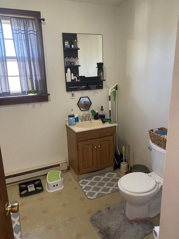 half bath featuring baseboard heating, vanity, toilet, and tile patterned floors