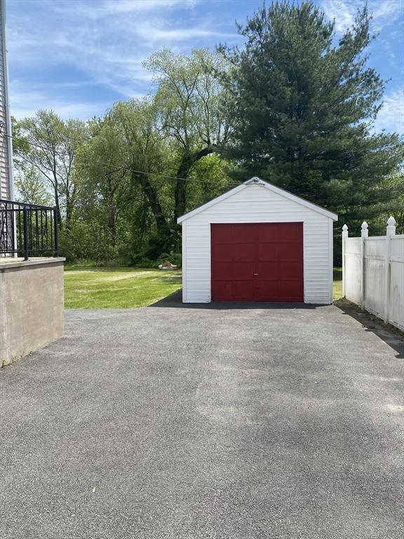 detached garage with fence and asphalt driveway