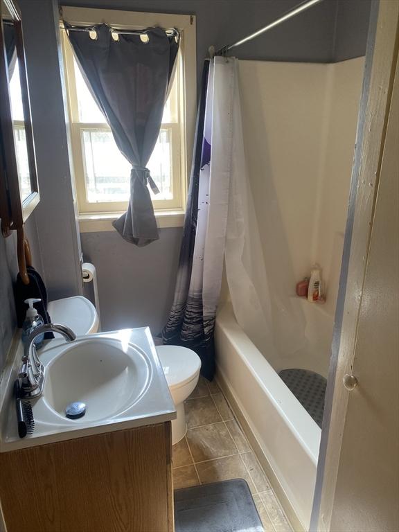 full bathroom featuring toilet, tile patterned floors, vanity, and shower / tub combo with curtain