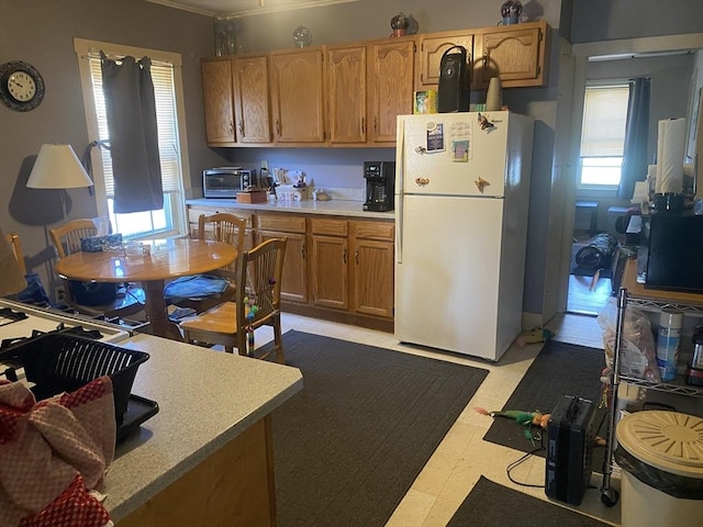 kitchen with freestanding refrigerator, light countertops, ornamental molding, and light flooring