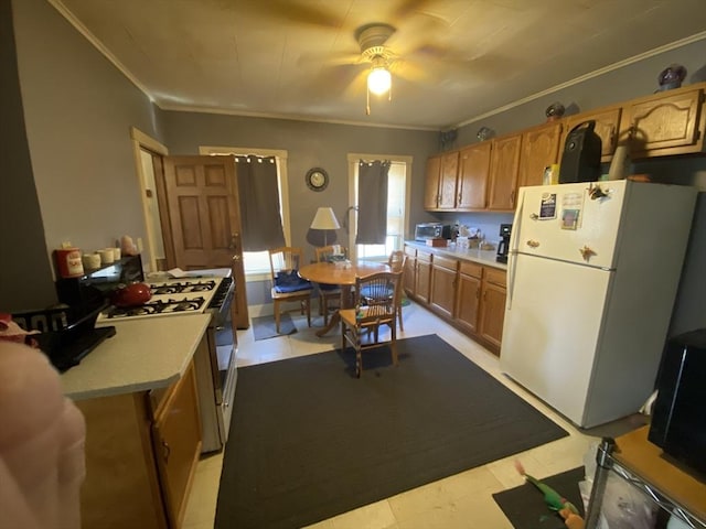 kitchen with white appliances, ceiling fan, light countertops, ornamental molding, and brown cabinets