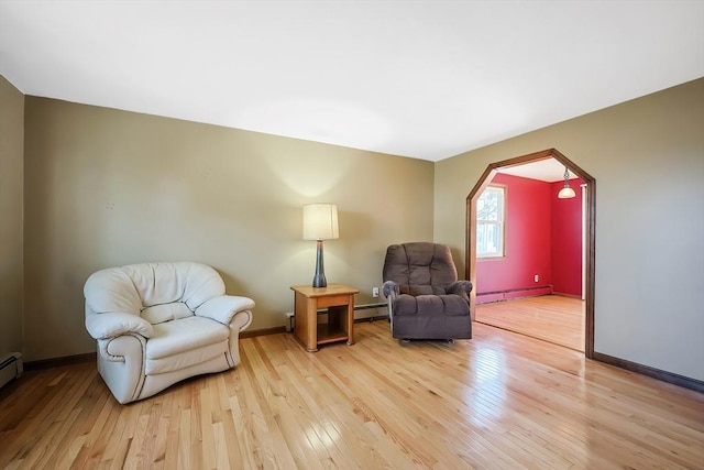 living area featuring baseboard heating, light wood-type flooring, and baseboards