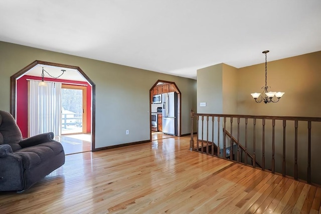 living room featuring baseboards, a notable chandelier, and light wood-style flooring