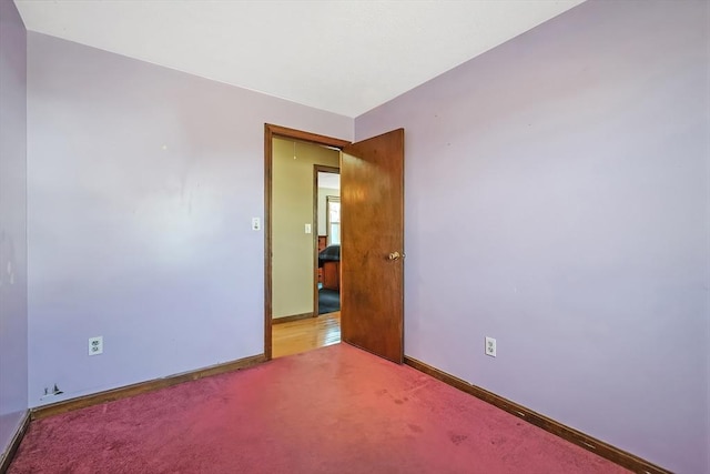 spare room featuring baseboards and light carpet