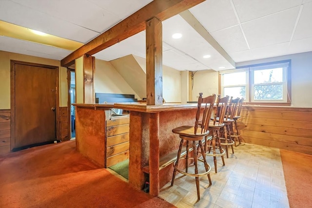 bar featuring wooden walls, beam ceiling, recessed lighting, a bar, and wainscoting