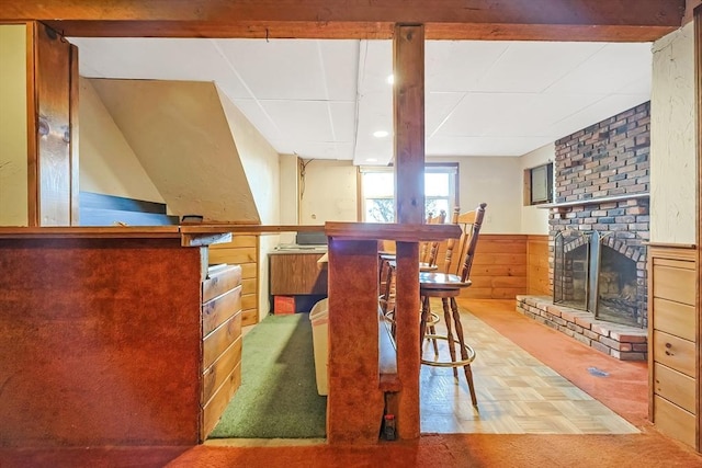 dining area with a wainscoted wall, a brick fireplace, and wood walls