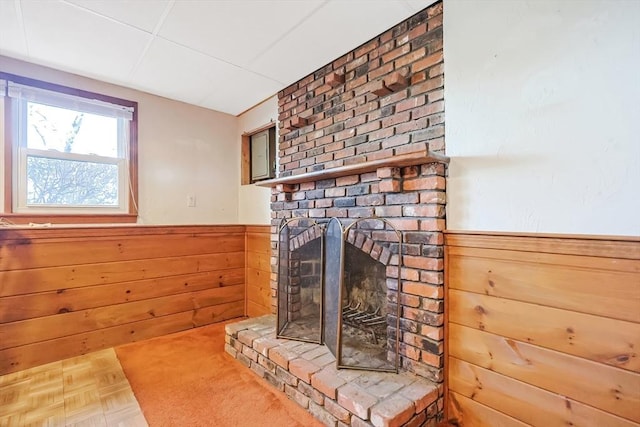 interior details featuring a wainscoted wall, wooden walls, and a brick fireplace