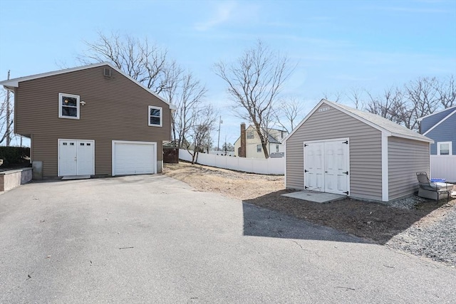 garage featuring aphalt driveway and fence