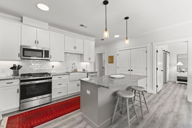 kitchen with sink, stainless steel appliances, light stone countertops, white cabinets, and a kitchen island