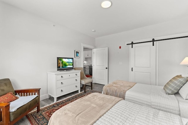 bedroom with wood-type flooring and a barn door