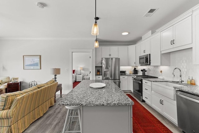 kitchen with pendant lighting, white cabinets, a kitchen bar, a center island, and stainless steel appliances