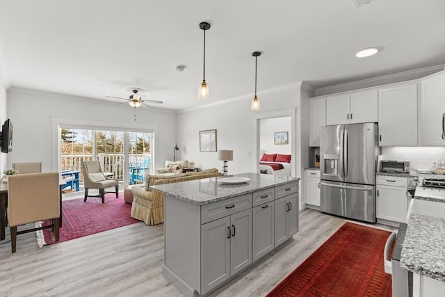 kitchen featuring crown molding, a center island, stainless steel refrigerator with ice dispenser, white cabinets, and decorative light fixtures